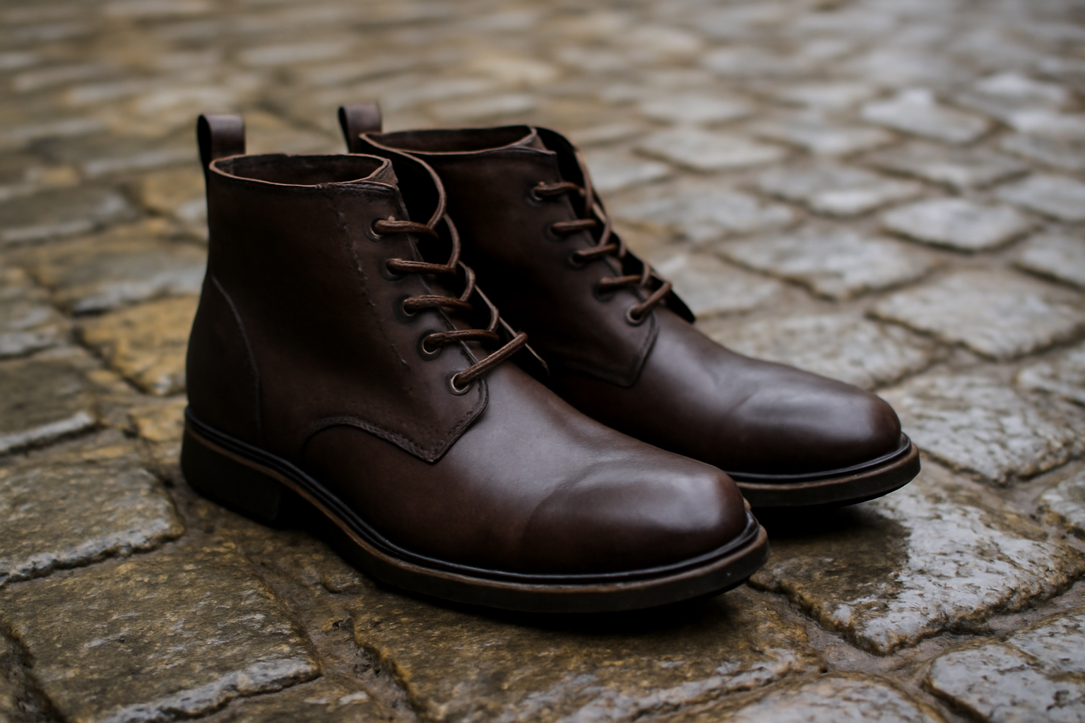 paire de bottines posée sur pavés humides