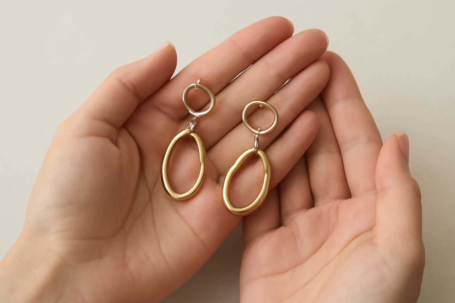 mains tenant des boucles d'oreilles sur fond neutre