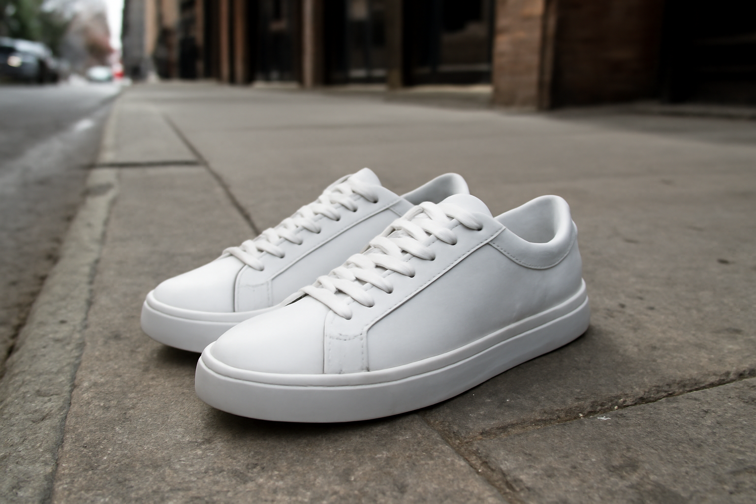 paire de baskets blanches posée sur trottoir urbain