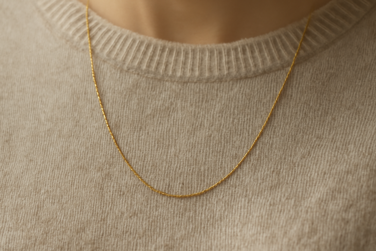 collier fin posé sur pull monochrome