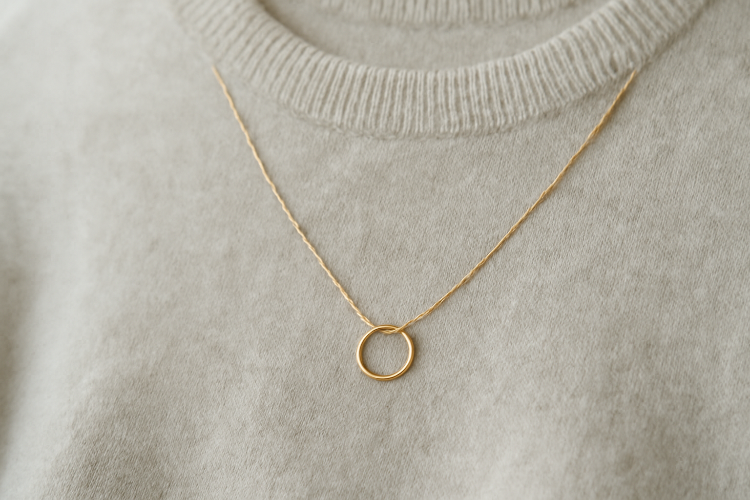 collier minimal posé sur un pull monochrome